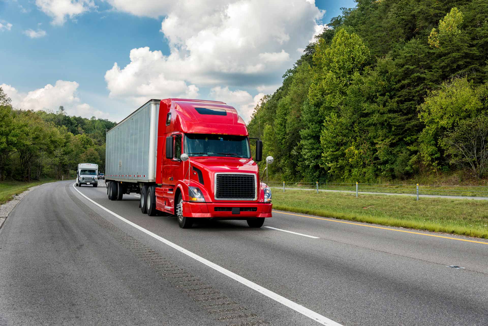 Red semi-truck driving down highway